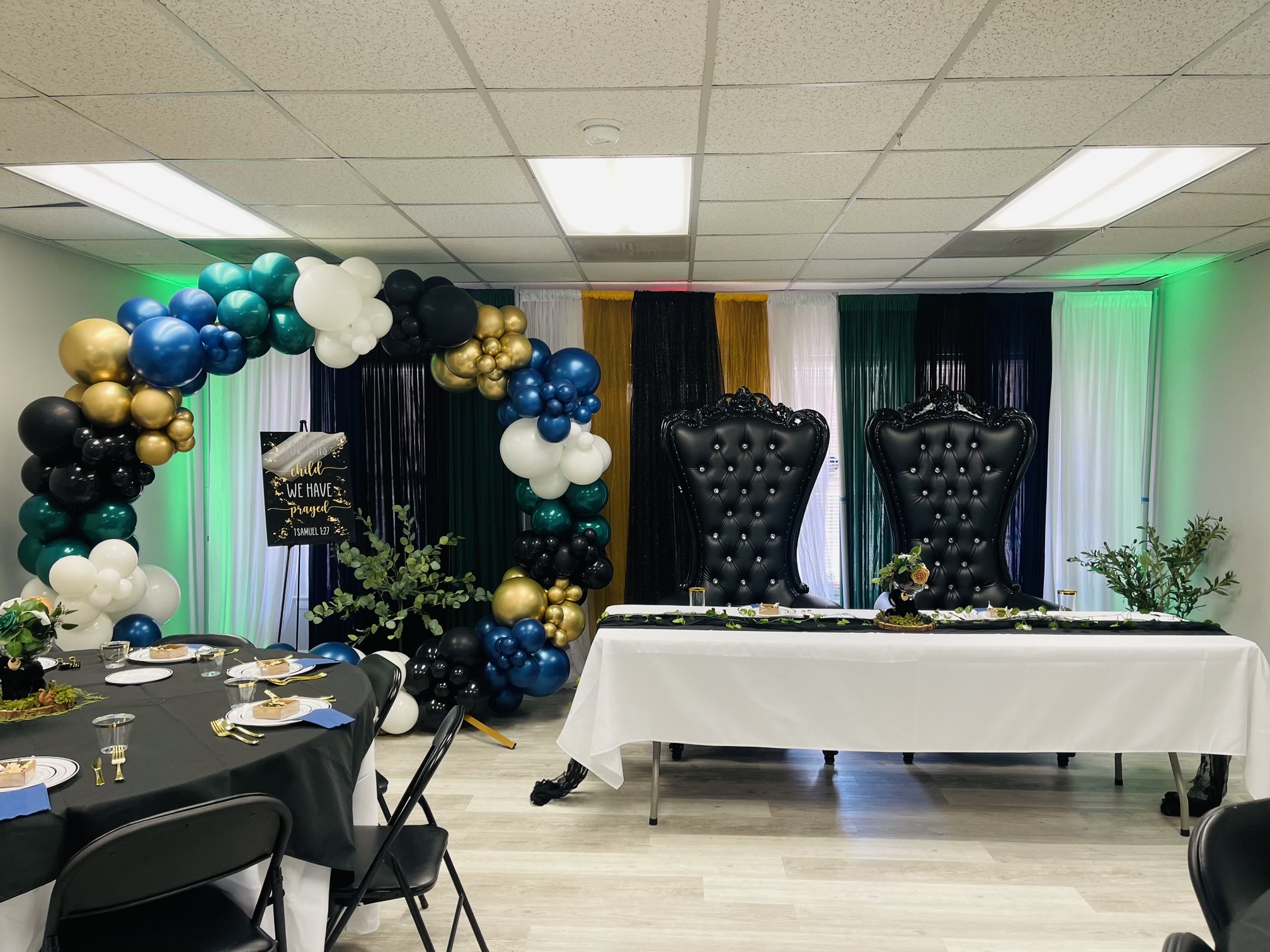 Blue, green, and gold balloon decor with seating and buffet setup