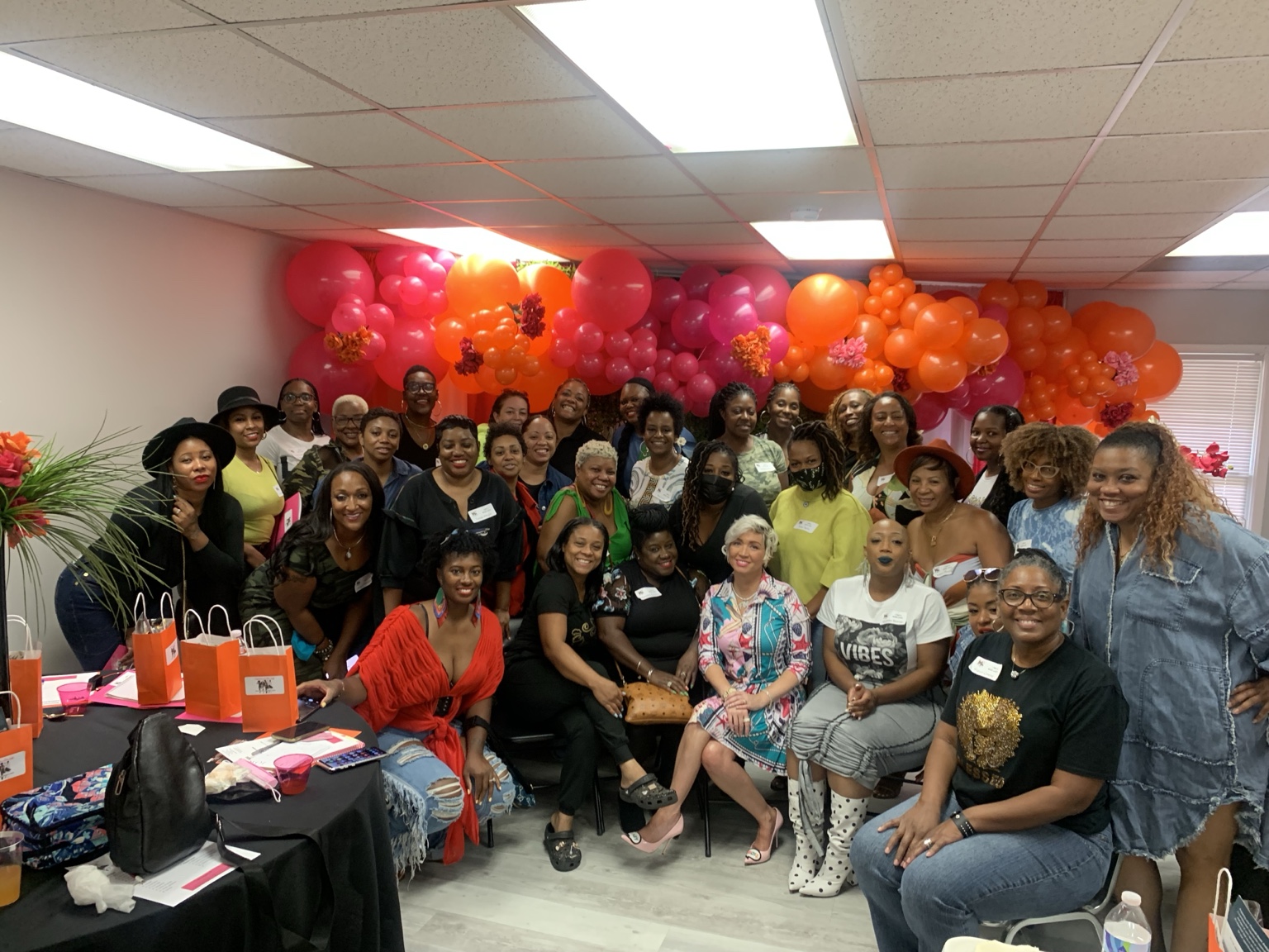 Group gathering with a bright pink and orange balloon backdrop