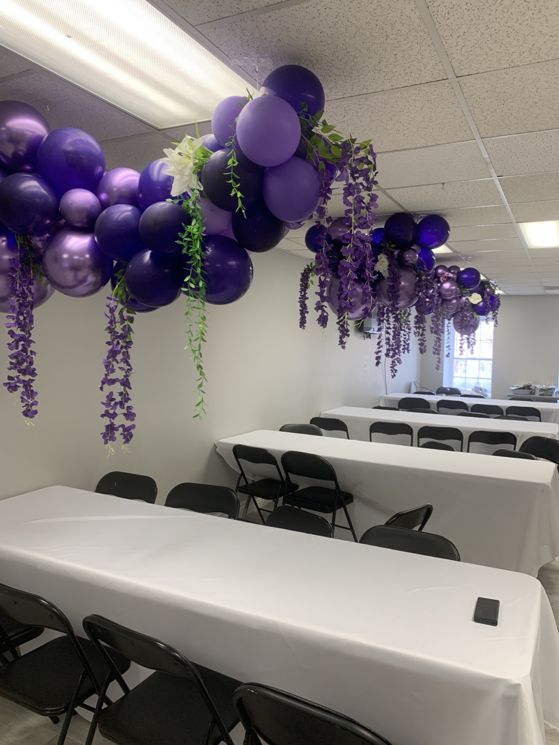 Classroom-style seating beneath purple balloon and floral decorations
