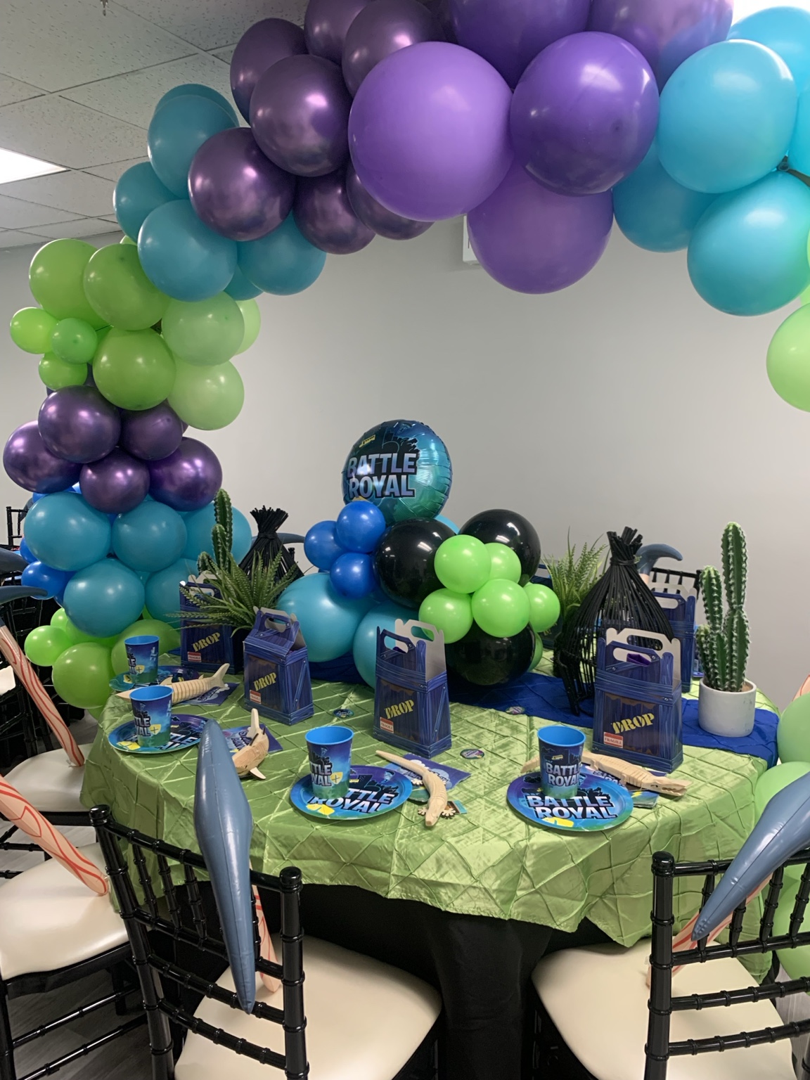 Purple, blue, and green balloon arch over a themed birthday table