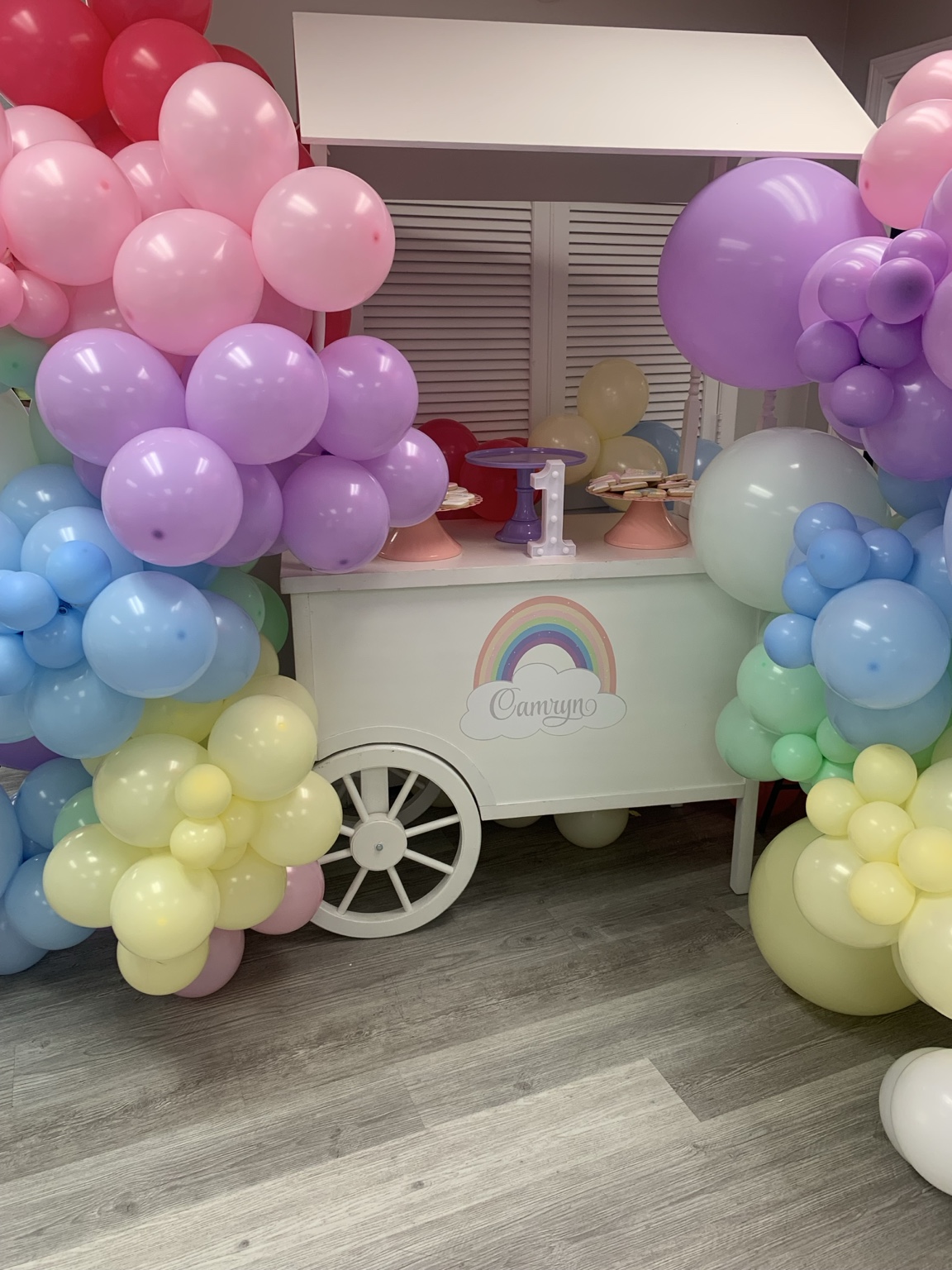 Pastel balloon display framing a birthday treat cart